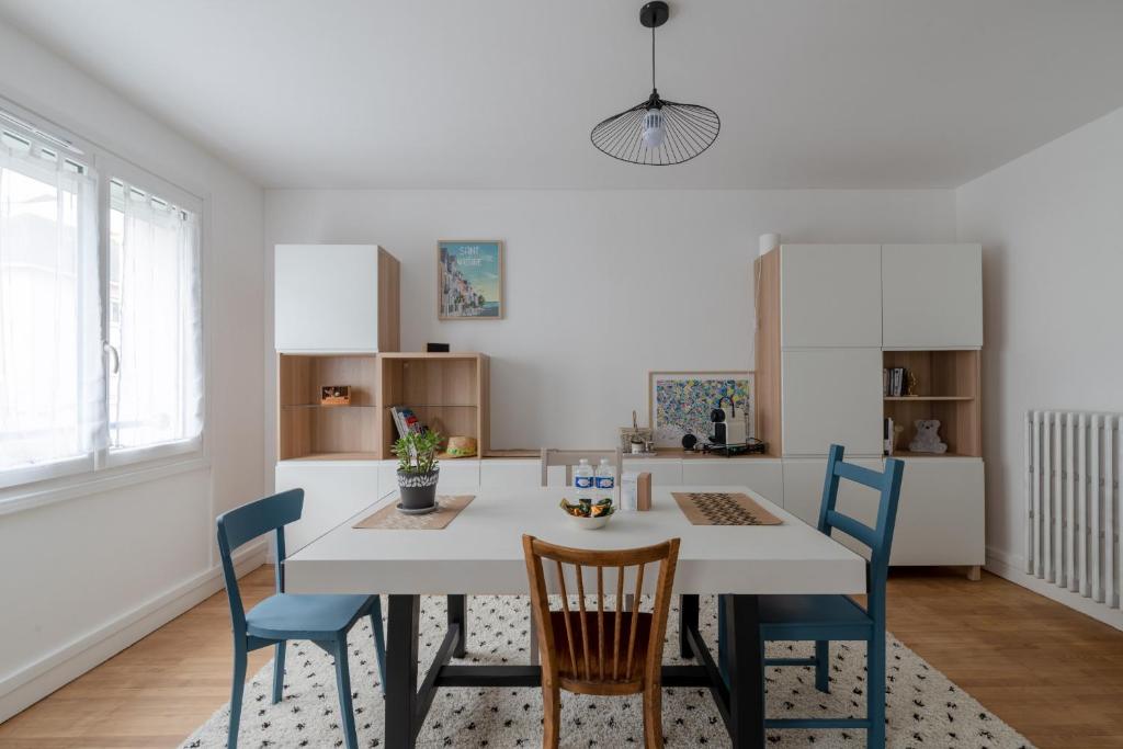 cocina con mesa blanca y sillas azules en Appartement lumineux centre de Saint-Nazaire en Saint-Nazaire