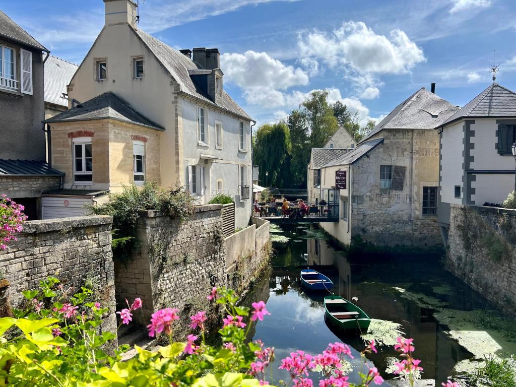 un canal dans une ville avec des maisons et des fleurs dans l'établissement La maison au bord de l Aure, à Bayeux