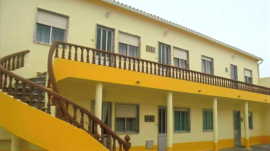 un edificio con una escalera amarilla en su lateral en Baleal Sol Alojamentos, en Baleal