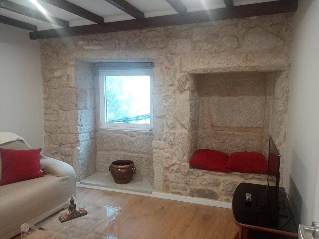 a living room with a stone wall with two red pillows at CASA PEREIRAS in Pontevedra
