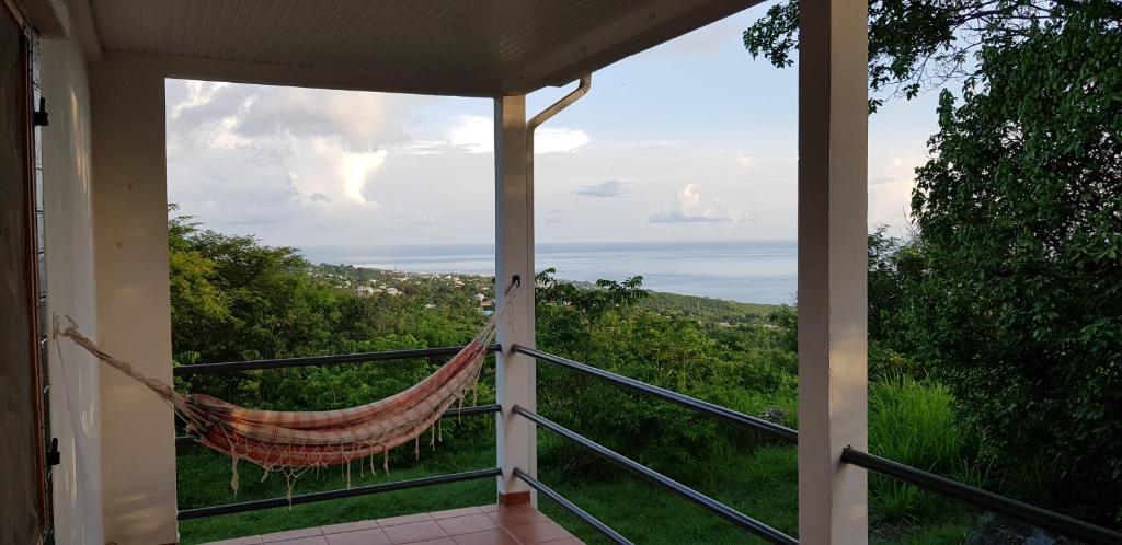 a hammock on a porch with a view of the ocean at Paisible maison à Vieux-Habitants in Vieux-Habitants