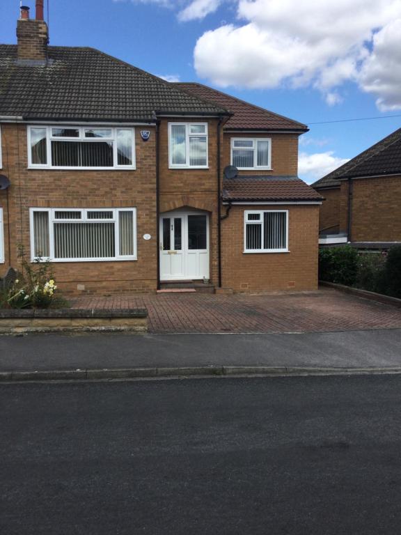 a brown brick house with white windows and a street at Large 4 bedroom home in Boston Spa village In-between York, Harrogate and Leeds, Sleeps 9 in Boston Spa