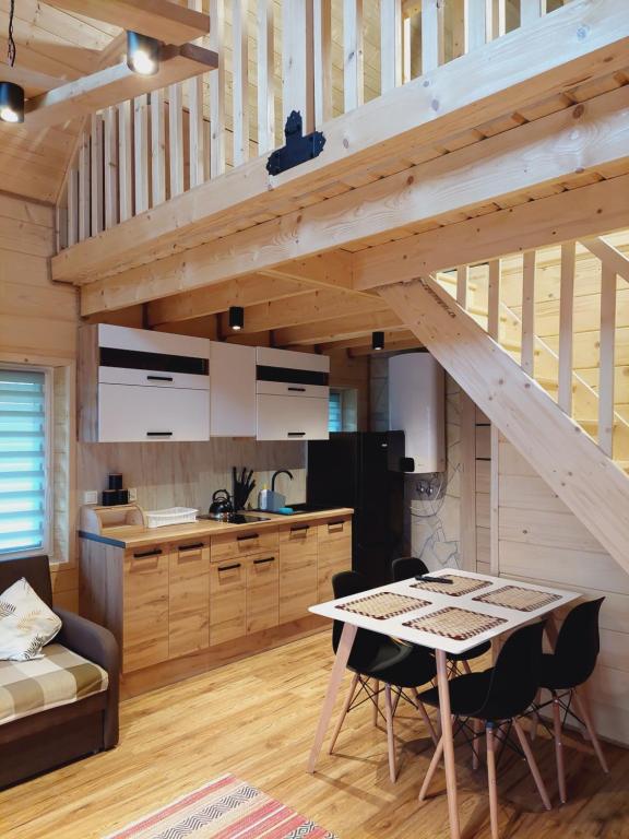 a kitchen and living room with a wooden staircase at Domeczek Tymoneczek in Ustrzyki Dolne