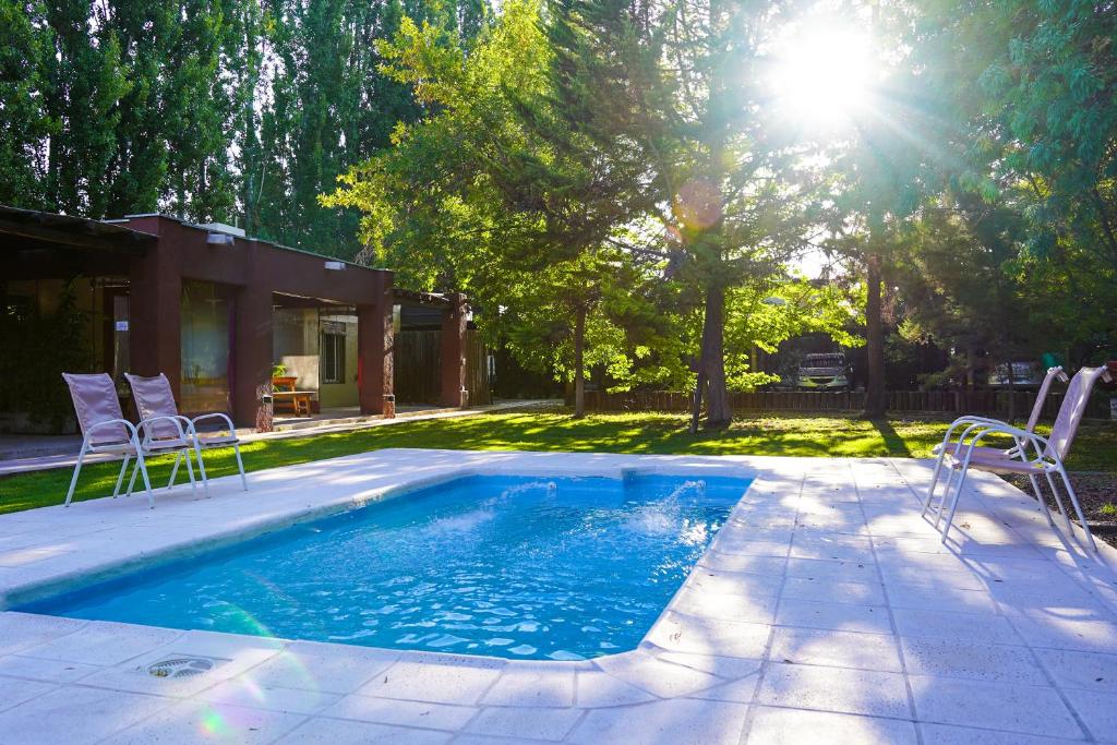 - une piscine avec des chaises et le soleil dans une cour dans l'établissement Cabañas Parque Vistalba, à Luján de Cuyo