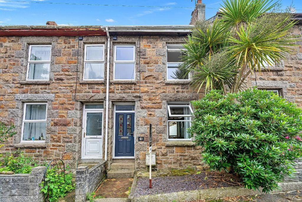 a brick house with a blue door and a palm tree at Finest Retreats - Poppy Cottage of Penzance in Penzance