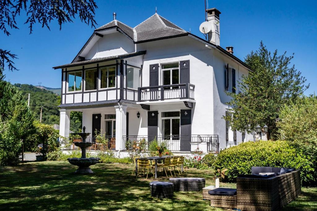 Biały dom ze stołem i krzesłami na dziedzińcu w obiekcie Luxury Pyrenees Villa, Tourmalet, gardens, gym w mieście Adast