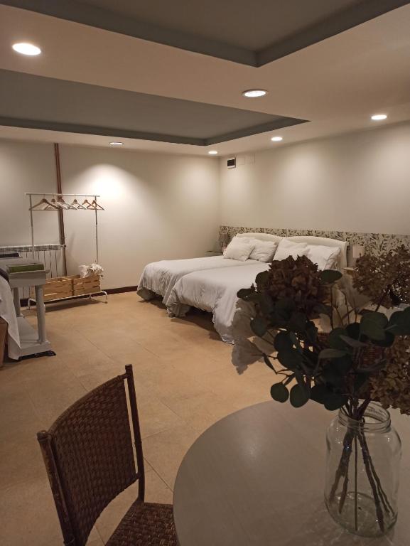 Un dormitorio con una cama y una mesa con un jarrón de flores en Apartamento independiente con jardín privado en Oviedo