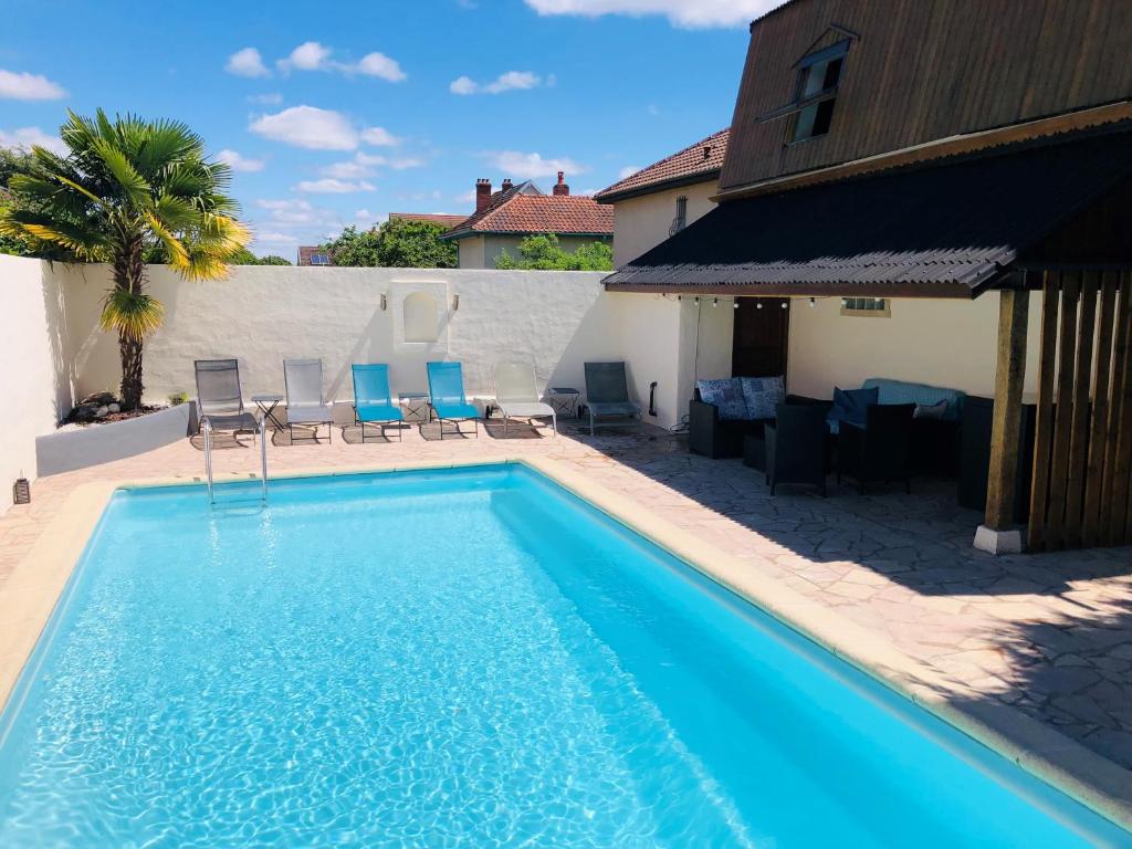 a swimming pool with blue chairs and a house at Chambres d'Hôte Dijon Clair de Lune in Chenôve