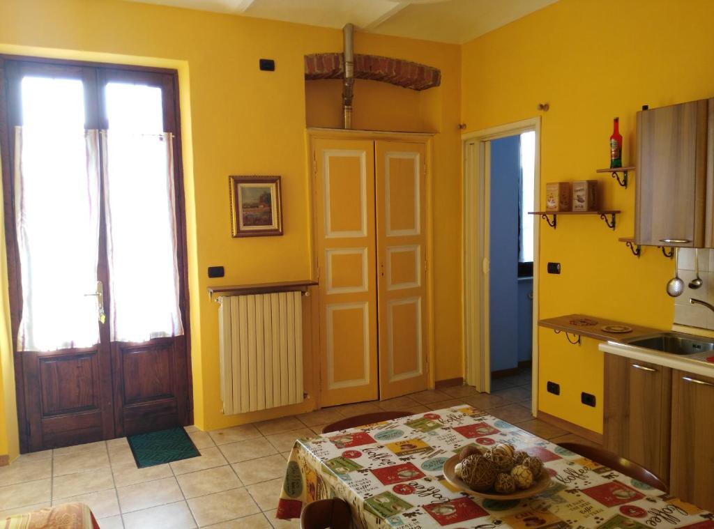 a kitchen with yellow walls and a table and a door at Casa Mauri in Asti