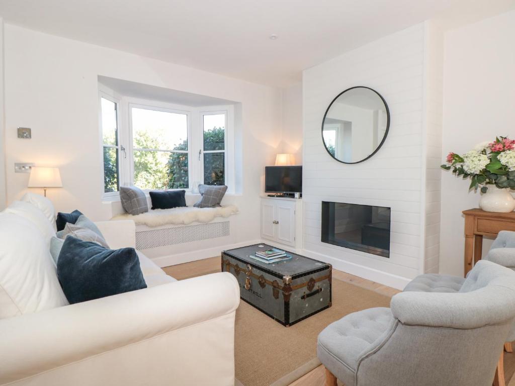 a living room with white furniture and a fireplace at Marroy in Salcombe