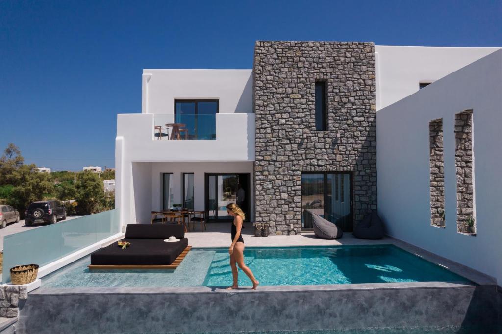 una donna che cammina davanti a una casa con piscina di Milestones Naxos a Naxos Chora