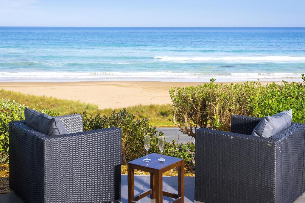 two chairs and a table with a view of the beach at Seafarers Getaway in Apollo Bay