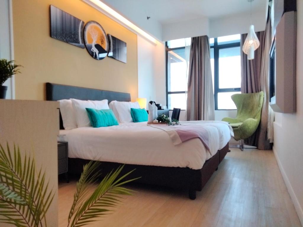 a hotel room with a large bed and a green chair at CentreStage PJ by HomeBrickz in Petaling Jaya