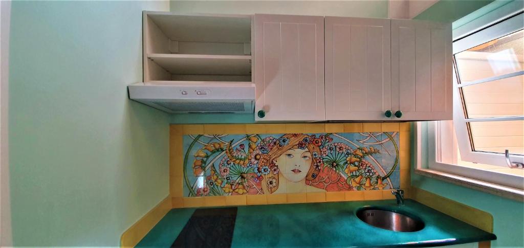 una cocina con fregadero y una pintura en la pared en B&B Les Saisons de Jade, en Nocera Superiore