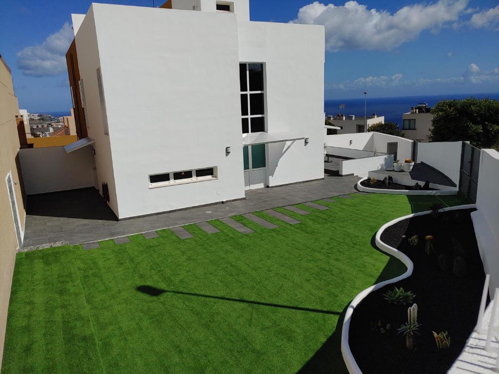 una casa blanca con un patio de césped verde en LUXURY DUPLEX ATLANTIC FOUR SEASONS, en Santa Cruz de Tenerife