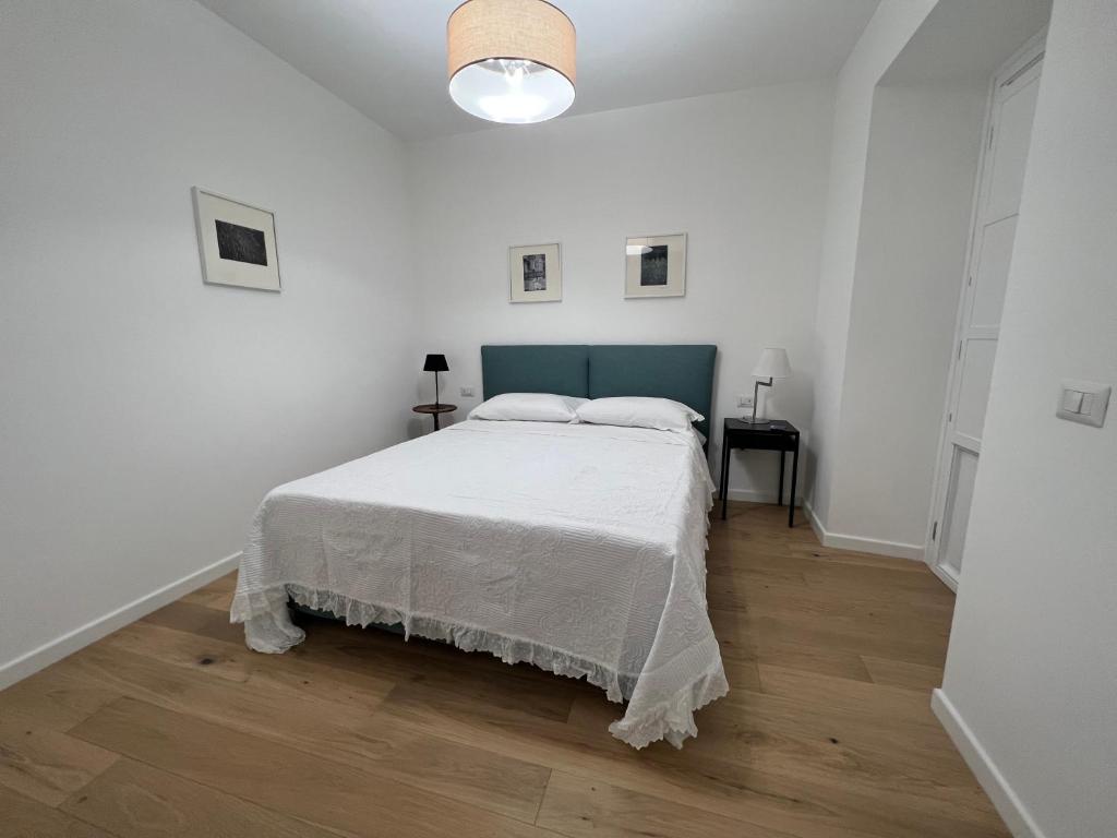 ein weißes Schlafzimmer mit einem Bett mit blauem Kopfteil in der Unterkunft AT HOME COLOSSEO in Rom