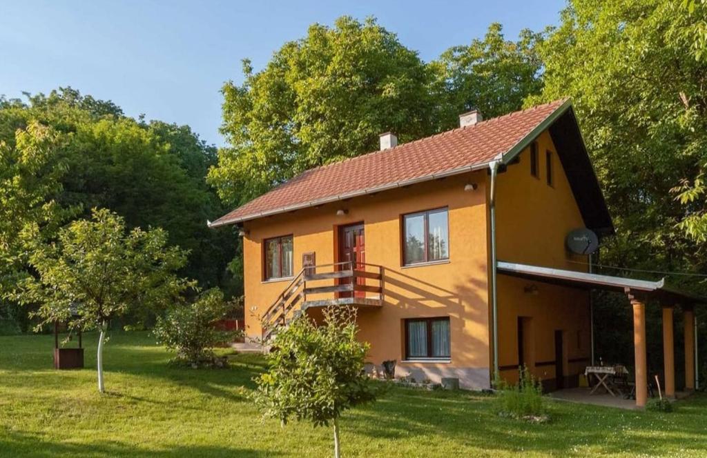 a yellow house with a staircase in a yard at Planinska kuca Rasovo Fruska Gora in Sremska Mitrovica