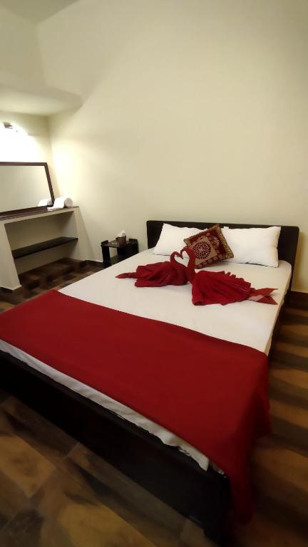 a large bed with a red blanket on it at Arangan Kudil in Tiruchirappalli