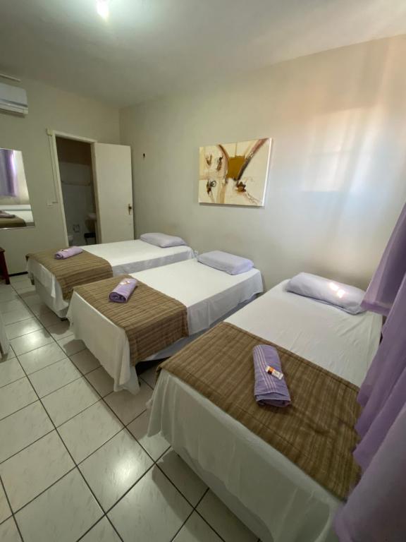 um quarto de hotel com três camas com guardanapos roxos em Center 1 Hotel em Fortaleza