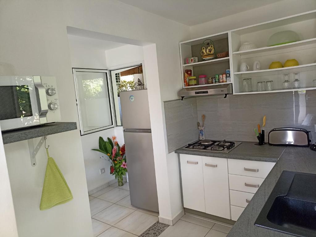 a kitchen with white cabinets and a refrigerator at Bungalow Milo in Bouillante