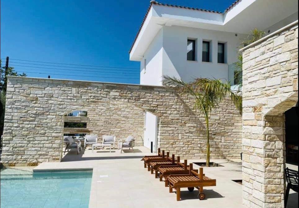 une maison avec une piscine à côté d'un mur en pierre dans l'établissement Paphos luxury contemporary villa, à Paphos