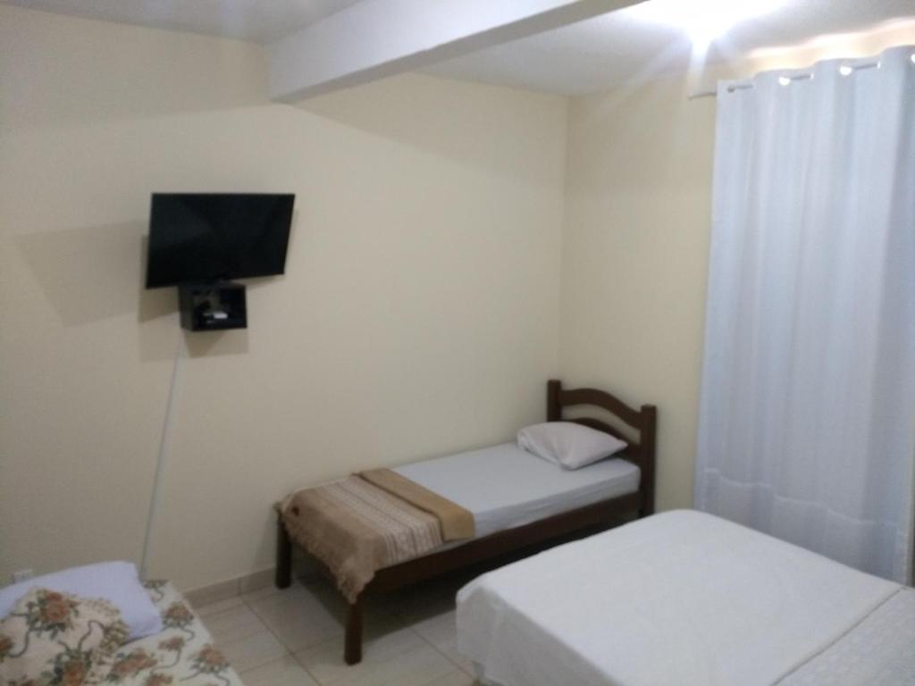 a room with two beds and a flat screen tv at Kitnets casa Amarela Imbassai in Imbassai