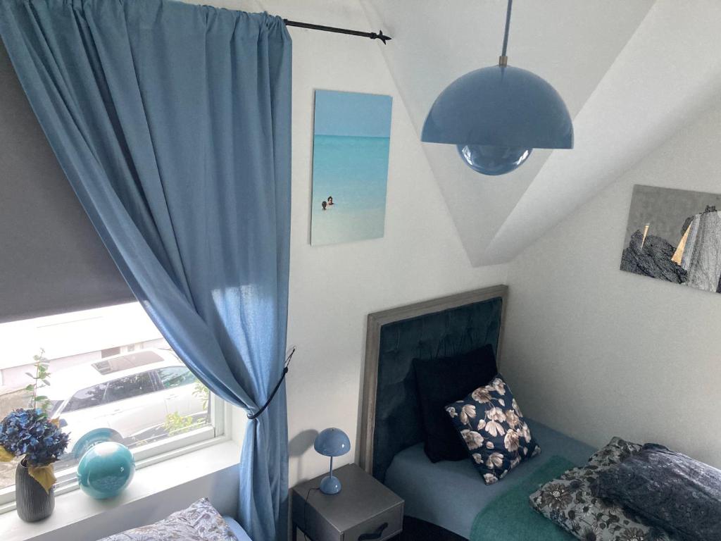 a bedroom with a blue curtain and a bed and a window at Downtown Historical House with Renovated apartments in Ålesund