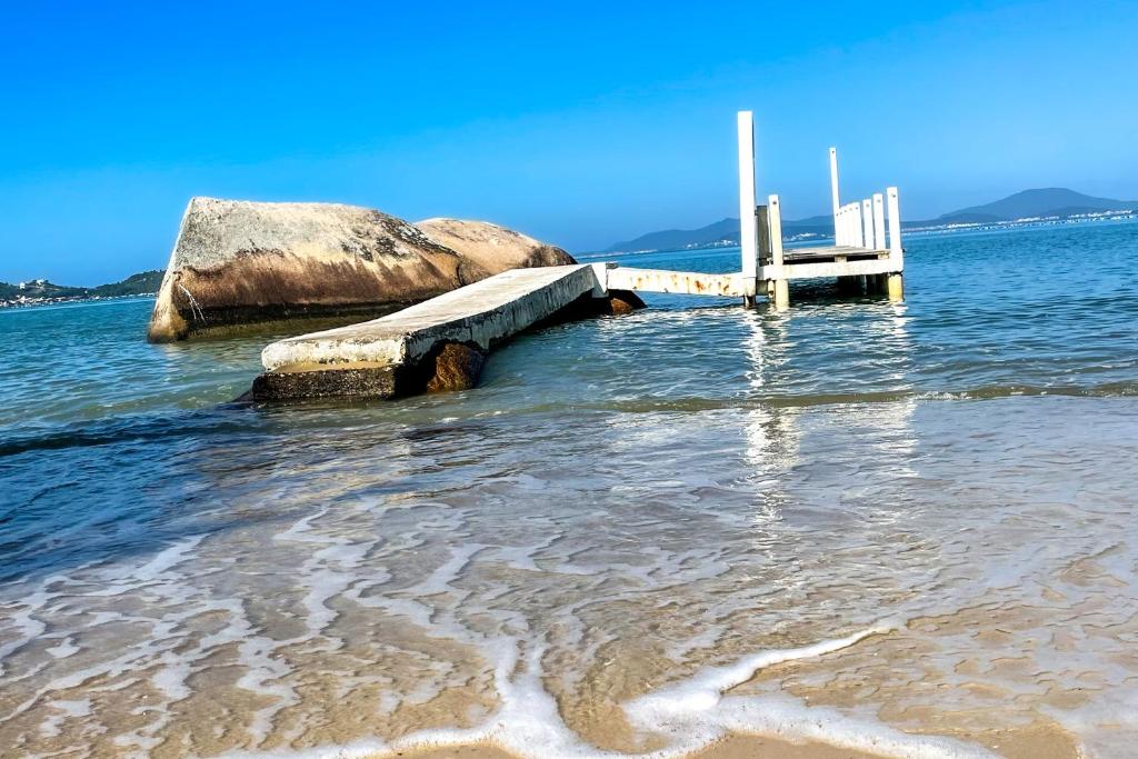 a dock in the water next to a beach at Pousada Recanto das Flores in Governador Celso Ramos