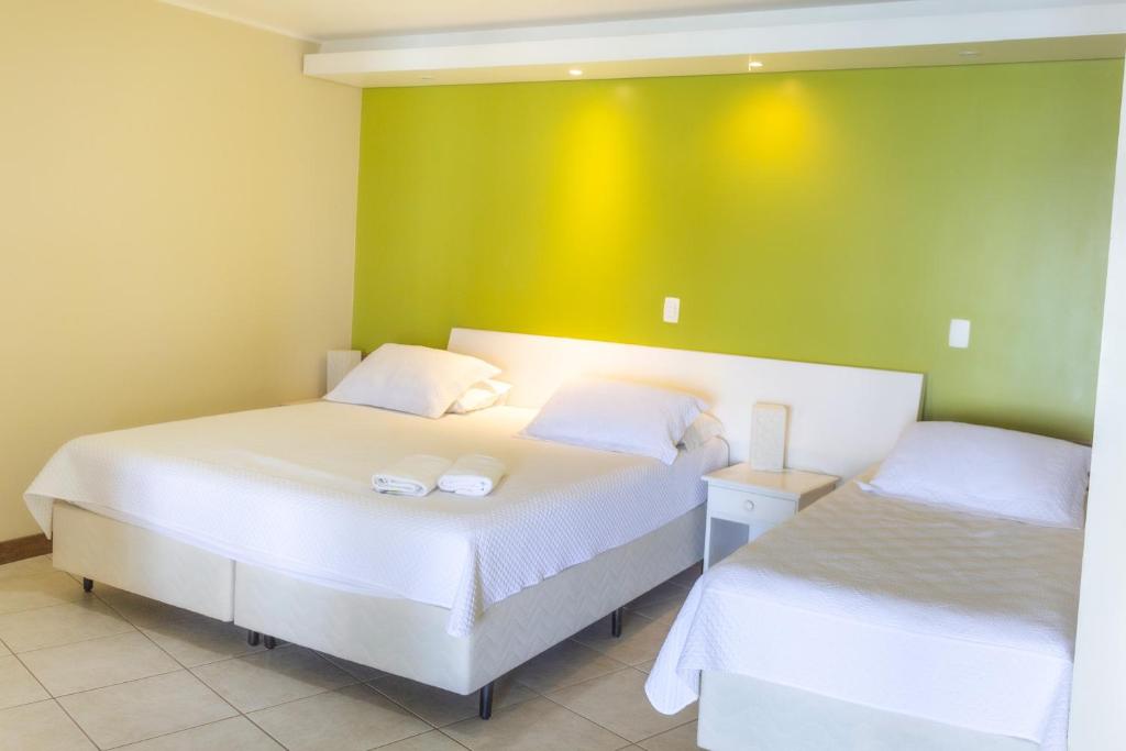 two beds in a room with a green wall at Pousada Recanto das Flores in Governador Celso Ramos