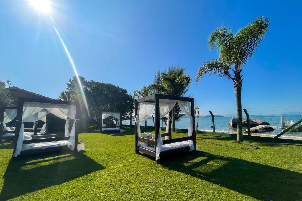 a couple of beds on the grass near the beach at Pousada Recanto das Flores in Governador Celso Ramos