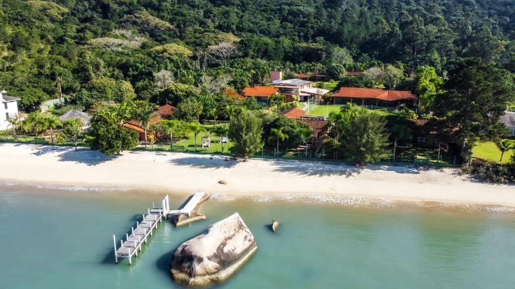 an island with a dock and a boat in the water at Pousada Recanto das Flores in Governador Celso Ramos