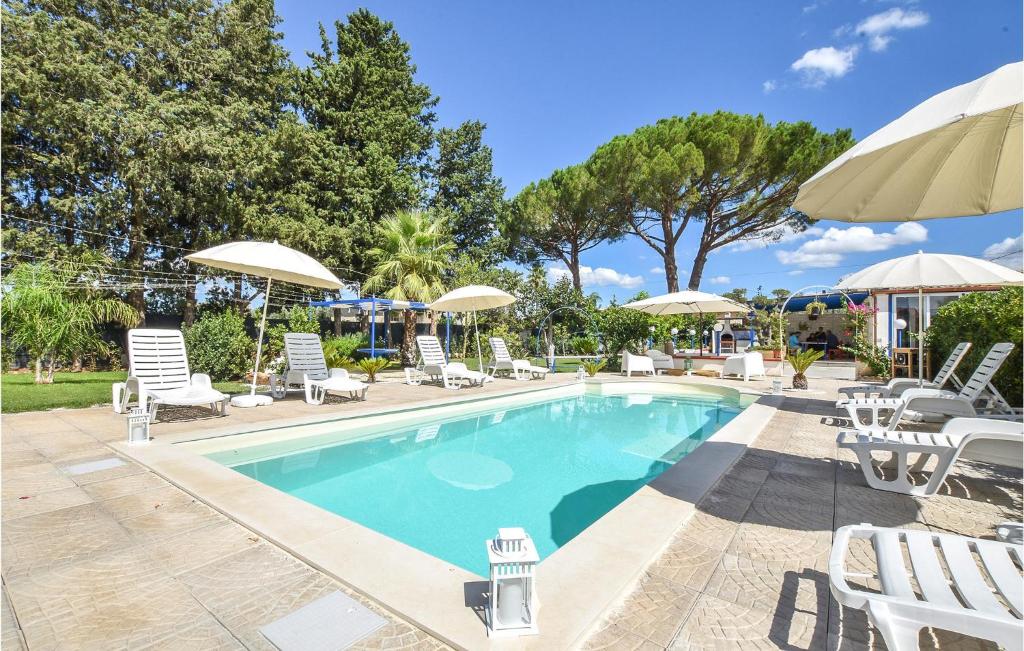 uma piscina com cadeiras e guarda-sóis em Amazing Home In Chiaramonte Gulfi With Private Swimming Pool, Can Be Inside Or Outside em Chiaramonte Gulfi