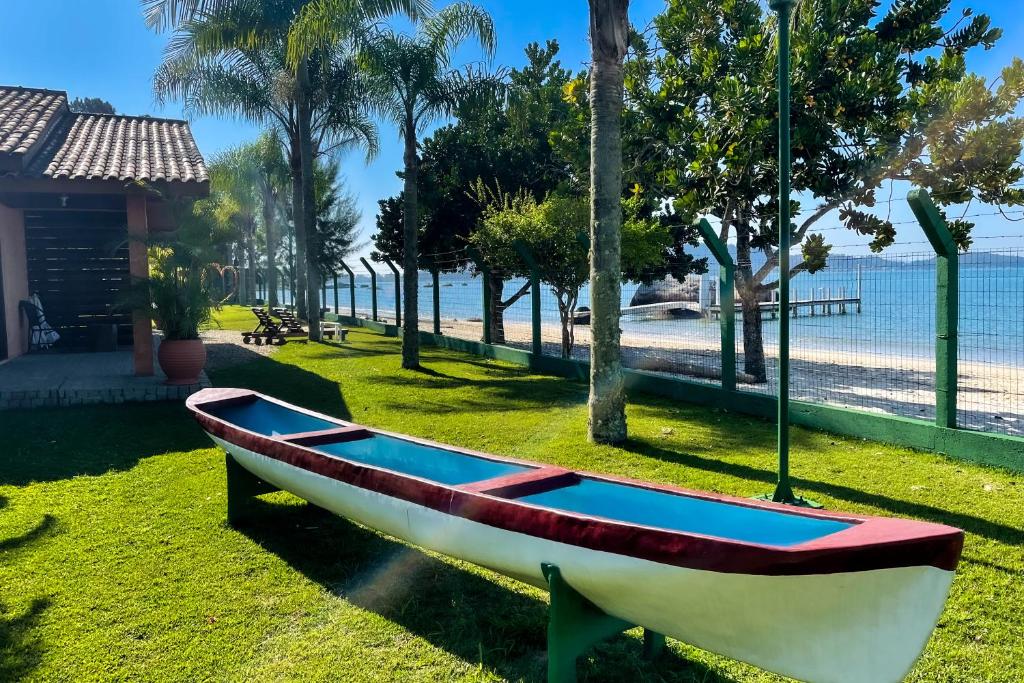 a boat sitting on the grass near the beach at Pousada Recanto das Flores in Governador Celso Ramos