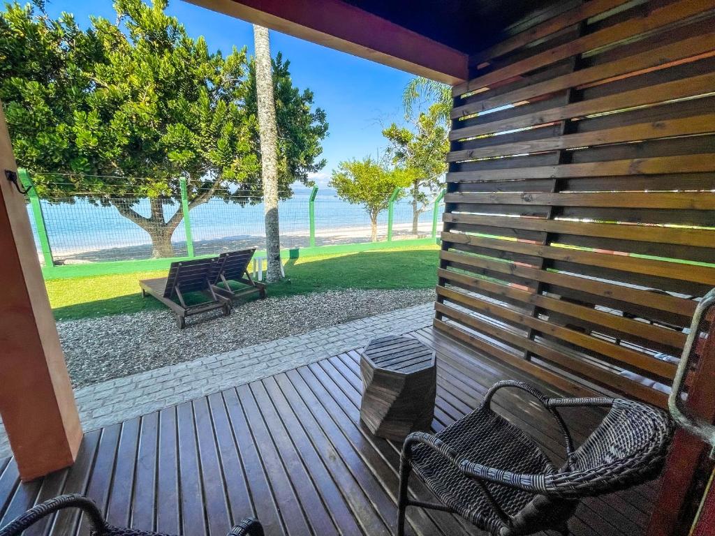 a wooden deck with two chairs and a swing at Pousada Recanto das Flores in Governador Celso Ramos