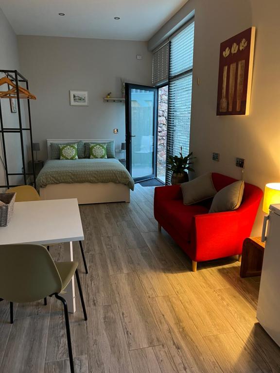 a living room with a red couch and a bed at Hugo Mews Bright Studio Apartment in Bray