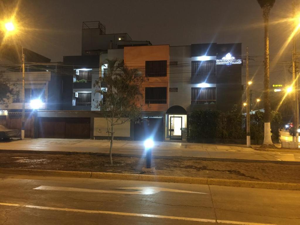 una persona che cammina per strada di notte con luci di Serenzza Hotel a Lima