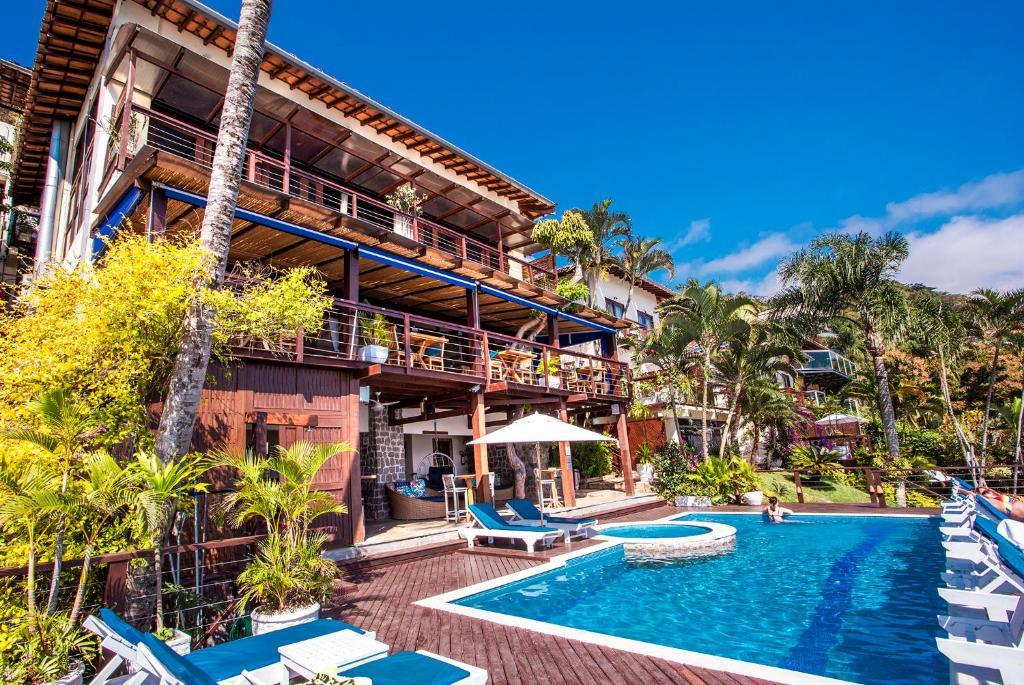 a resort with a pool and chairs and a building at Barra do Piuva Porto Hotel in Ilhabela