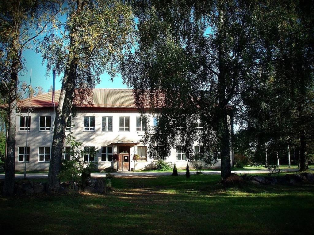 a large white building with trees in front of it at Roosu Talu Accommodation in Sulbi