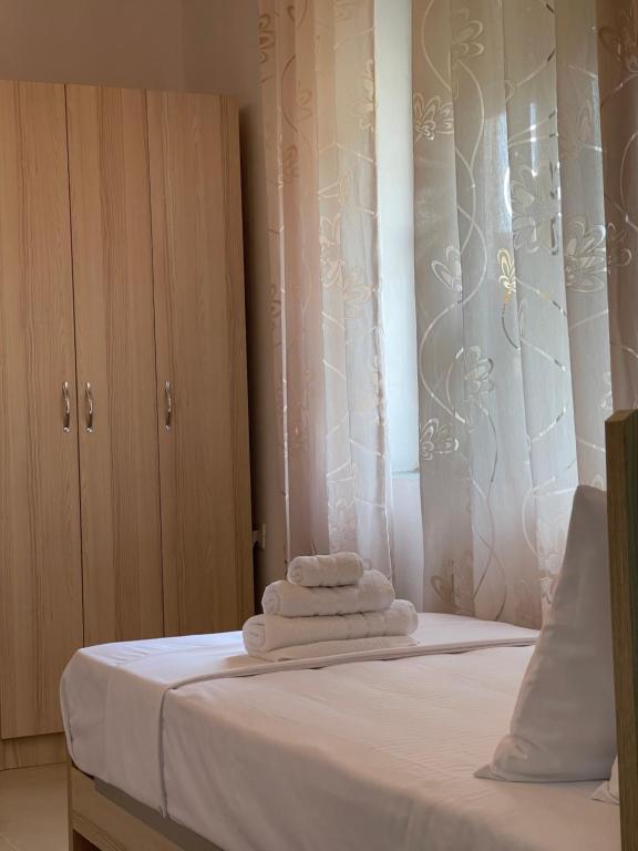 a bedroom with a bed with white sheets and a window at Skrapari Studio Apartment in Çorovodë