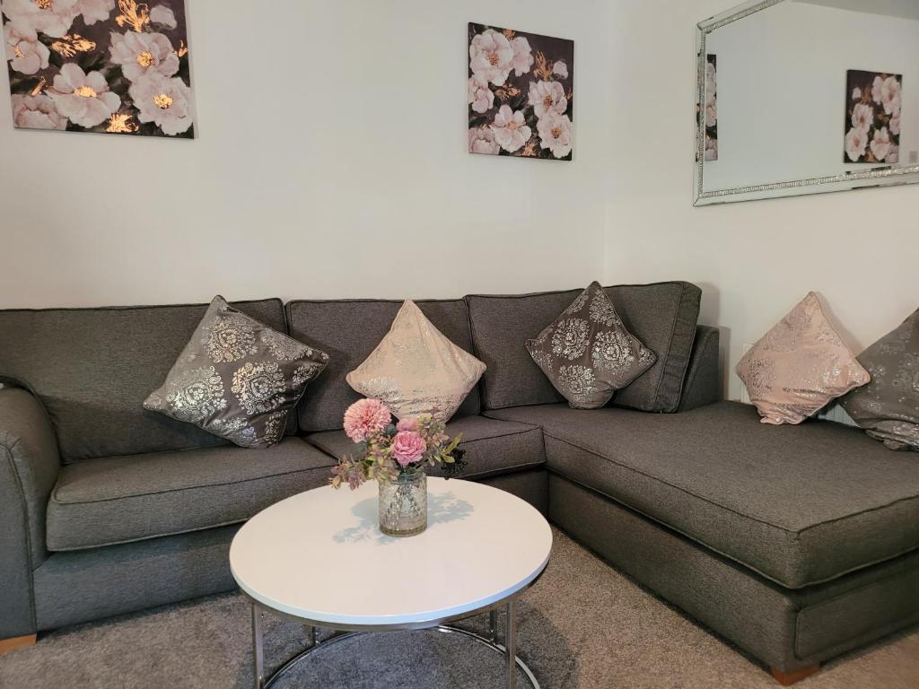 a living room with a couch and a table with flowers at Elegance apartments in West Cornforth