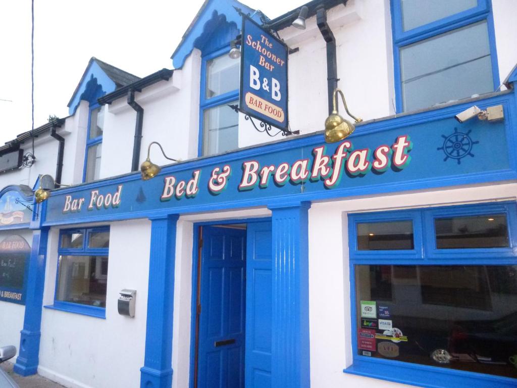 un edificio azul y blanco con un cartel de bed and breakfast en The Schooner Tavern, en Ballycotton