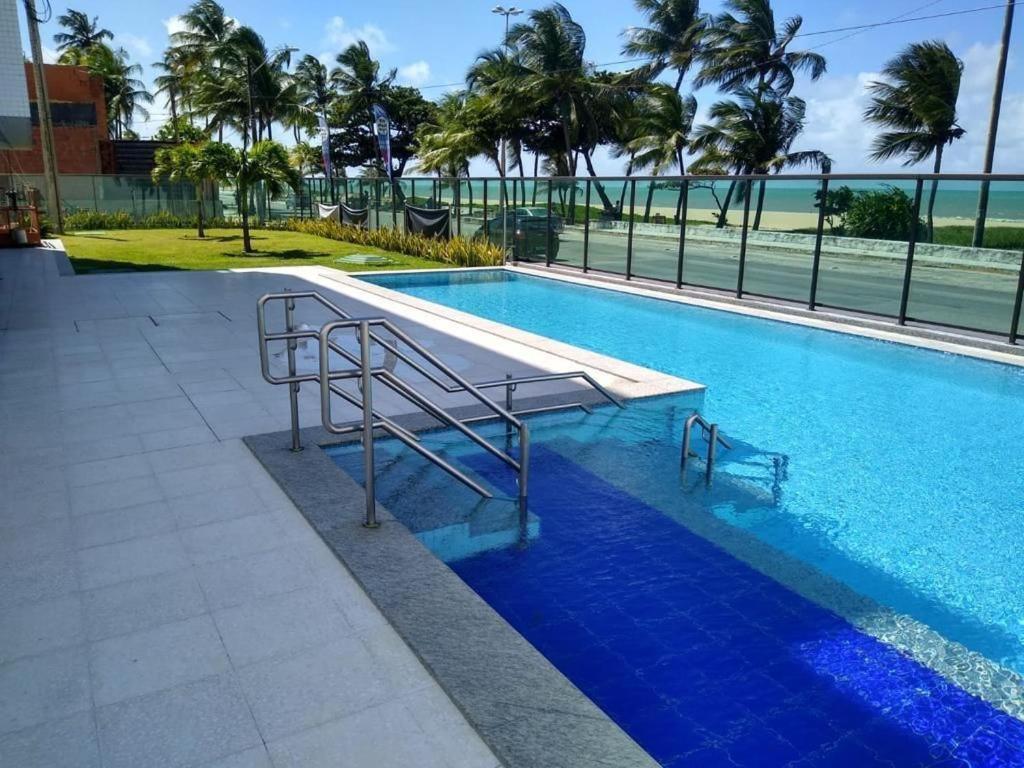 a swimming pool with a bench next to the ocean at Rio Park Avenue Residence, Piedade - By TRH Invest in Recife