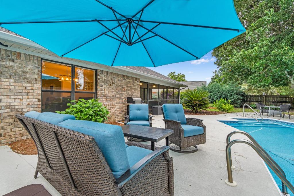 a patio with a table and chairs and a blue umbrella at Outdoor Oasis by Beaches in Gulf Breeze