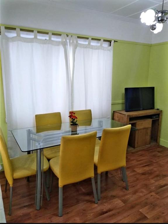 ein Esszimmer mit einem Glastisch und gelben Stühlen in der Unterkunft Inmuebles V&S in Río Gallegos