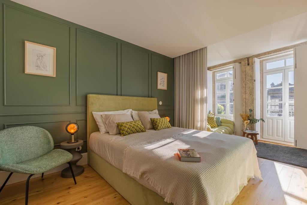 een groene slaapkamer met een bed en een stoel bij As Vizinhas Boutique Apartments in Porto
