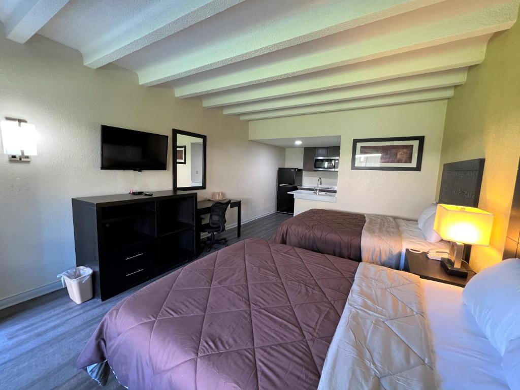 a hotel room with two beds and a flat screen tv at James River Inn & Suites in Newport News