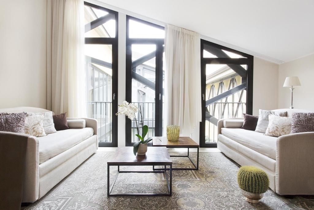 una sala de estar con 2 sofás blancos y una mesa. en Adriano Residence, en Bolonia