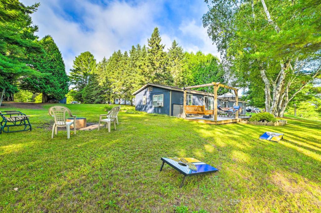 a yard with a house and a table and chairs at Riverfront Home with Dock about 6 Mi to Cheboygan! in Cheboygan