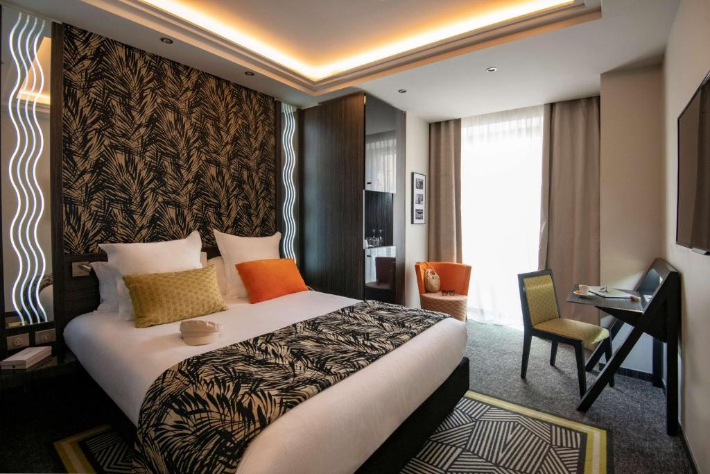 um quarto de hotel com uma cama grande e uma secretária em BW Premier Collection Mondial em Cannes