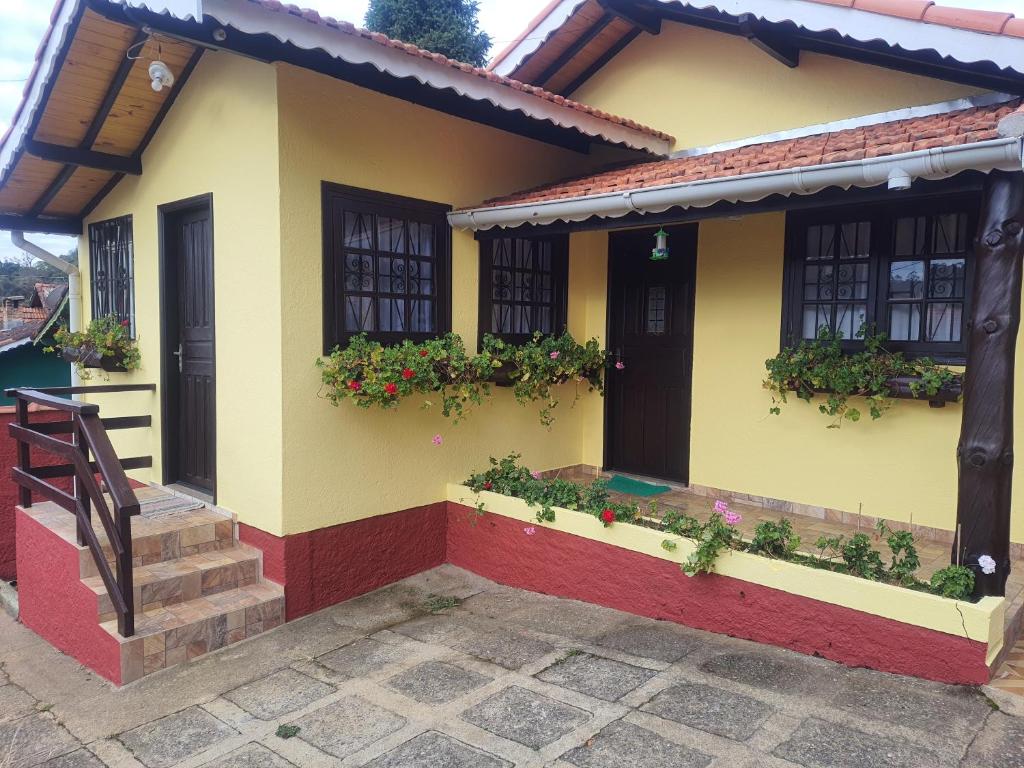 uma casa com flores ao lado dela em Chalés Juliana Casa 1 em Monte Verde